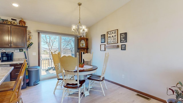 dining room with light wood-type flooring, lofted ceiling, and an inviting chandelier