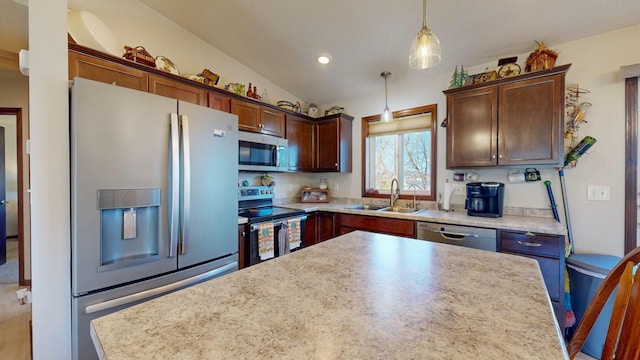 kitchen with stainless steel appliances, sink, hanging light fixtures, a kitchen island, and vaulted ceiling