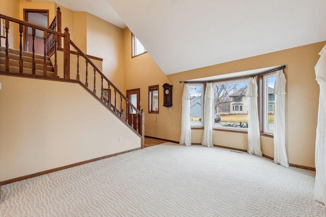 unfurnished living room featuring visible vents, a towering ceiling, stairs, baseboards, and carpet