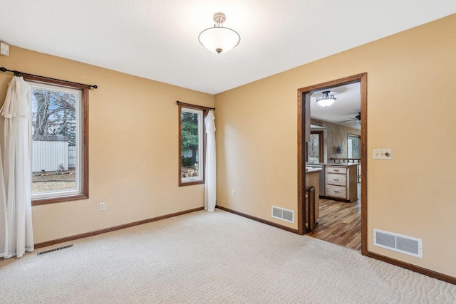 unfurnished room with light carpet, plenty of natural light, and visible vents