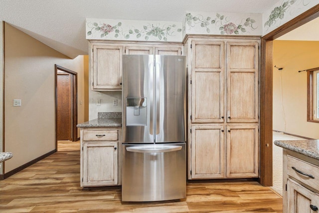 kitchen featuring light wood-type flooring, stainless steel fridge, baseboards, and a textured ceiling