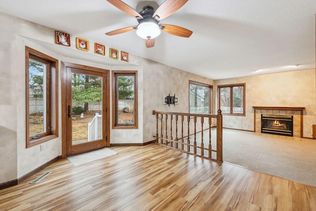 interior space featuring a tile fireplace, visible vents, baseboards, and wood finished floors