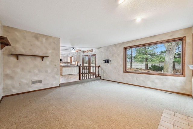 carpeted empty room featuring a healthy amount of sunlight, visible vents, and a textured ceiling