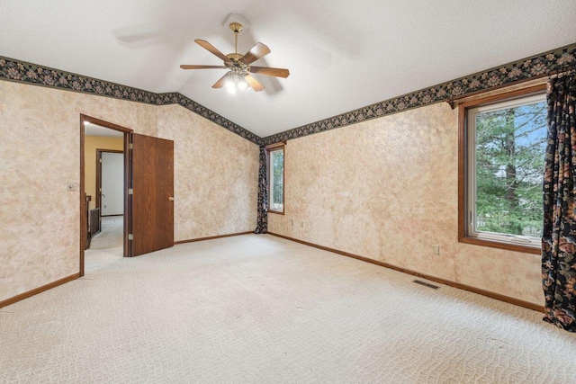 empty room with lofted ceiling, wallpapered walls, baseboards, and light colored carpet