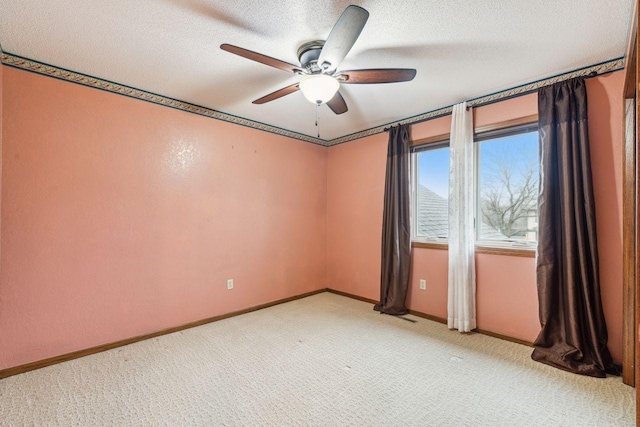 spare room with a ceiling fan, light carpet, a textured ceiling, and baseboards