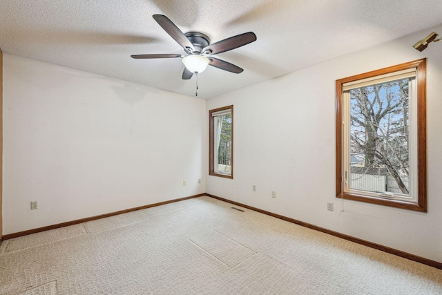 empty room with visible vents, light carpet, a textured ceiling, and baseboards