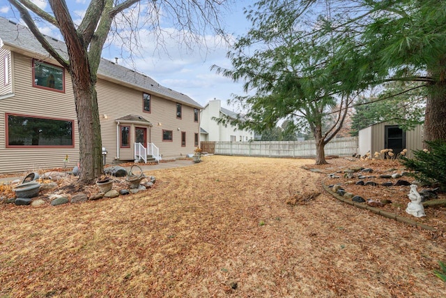 view of yard with entry steps, a storage shed, fence, and an outbuilding