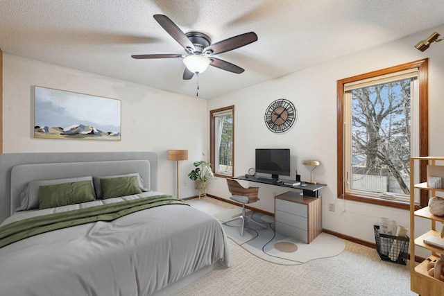 carpeted bedroom featuring a textured ceiling, a ceiling fan, and baseboards