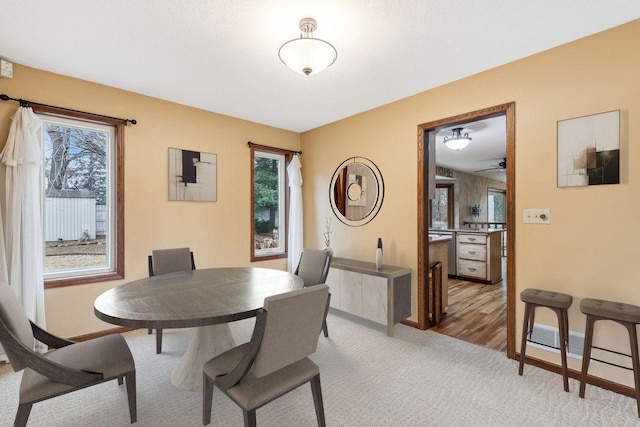 dining space featuring a wealth of natural light, light carpet, and baseboards