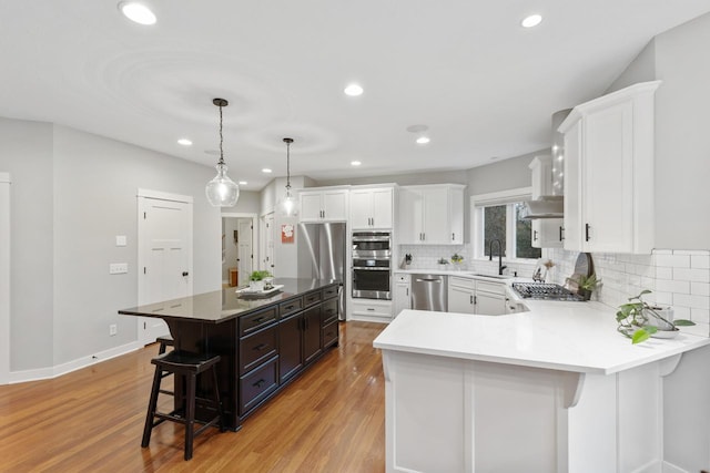 kitchen with white cabinetry, a kitchen island, pendant lighting, a breakfast bar, and sink