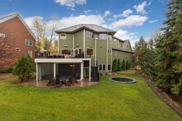 rear view of property with a wooden deck, a patio area, a fire pit, and a lawn