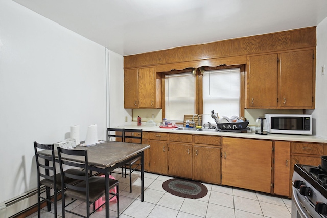 kitchen with a baseboard heating unit, stainless steel gas stove, sink, and light tile patterned floors