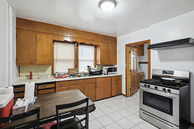 kitchen with range hood, stainless steel range with gas cooktop, sink, and light tile patterned floors