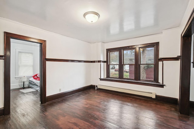 empty room featuring dark wood-type flooring, ornamental molding, and a baseboard heating unit