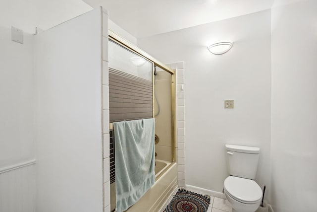 bathroom featuring tile patterned flooring, toilet, and bath / shower combo with glass door