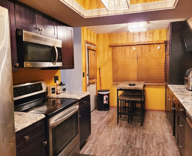 kitchen featuring light stone countertops, stainless steel appliances, and light hardwood / wood-style flooring