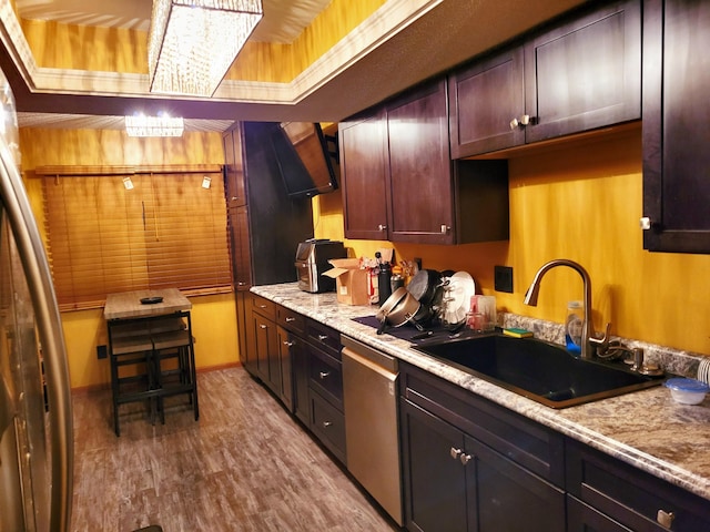 kitchen with hardwood / wood-style flooring, sink, appliances with stainless steel finishes, a raised ceiling, and crown molding