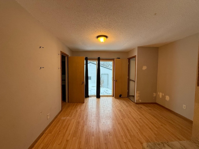 spare room with light hardwood / wood-style floors and a textured ceiling