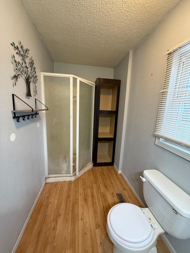 bathroom with a shower, hardwood / wood-style floors, a textured ceiling, and toilet