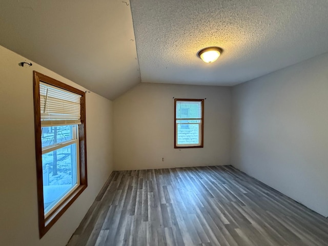 bonus room featuring vaulted ceiling, dark hardwood / wood-style flooring, and a textured ceiling