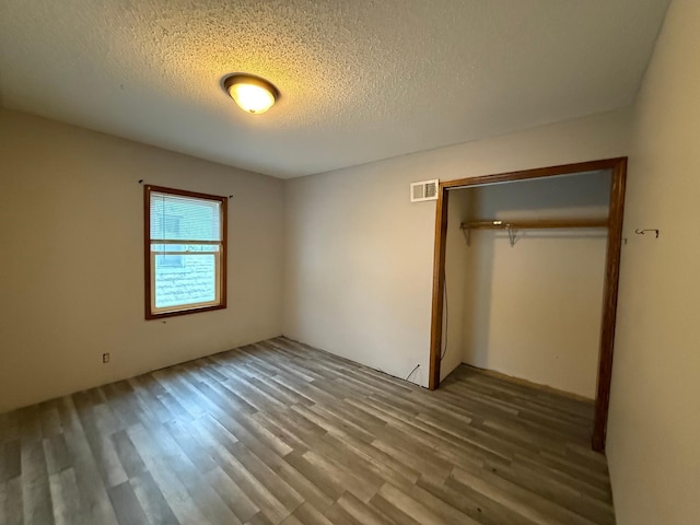 unfurnished bedroom featuring a textured ceiling, hardwood / wood-style flooring, and a closet