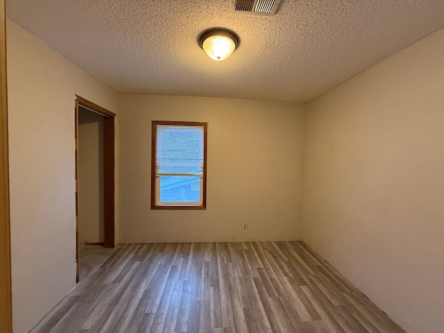 empty room featuring a textured ceiling and light hardwood / wood-style flooring