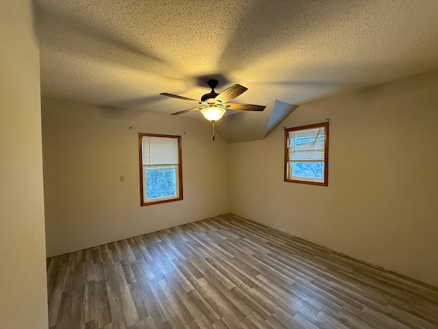 spare room with lofted ceiling, ceiling fan, hardwood / wood-style floors, and a textured ceiling