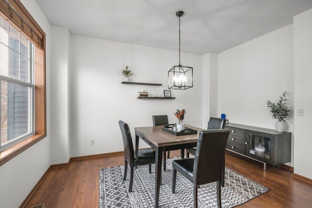 dining area with dark wood-type flooring, a notable chandelier, and a healthy amount of sunlight