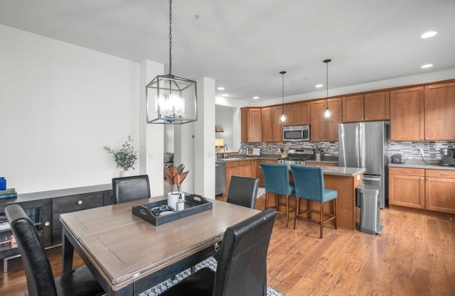 dining space featuring light hardwood / wood-style floors, sink, and an inviting chandelier