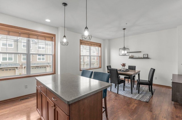 kitchen with a breakfast bar, wood-type flooring, decorative light fixtures, and a kitchen island