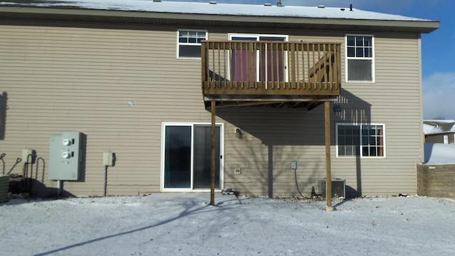 snow covered rear of property featuring a balcony