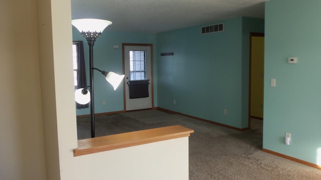 carpeted foyer entrance featuring a textured ceiling