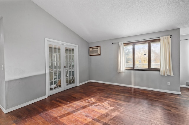 empty room featuring a textured ceiling, lofted ceiling, an AC wall unit, and dark wood-type flooring