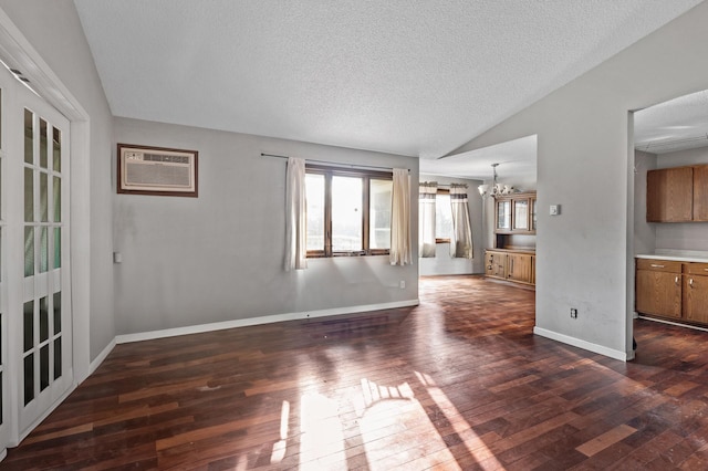 unfurnished living room with lofted ceiling, dark wood-type flooring, an AC wall unit, a textured ceiling, and a notable chandelier