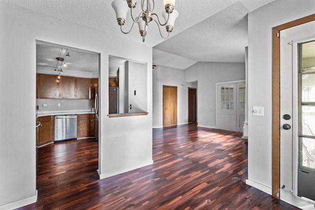 kitchen featuring a textured ceiling, vaulted ceiling, stainless steel dishwasher, and dark wood-type flooring