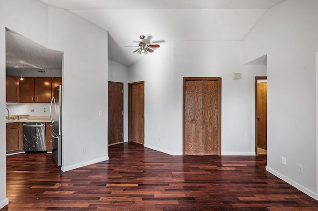 unfurnished living room with ceiling fan, a sink, baseboards, vaulted ceiling, and dark wood-style floors