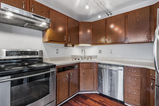 kitchen featuring dark wood finished floors, light countertops, appliances with stainless steel finishes, a sink, and under cabinet range hood