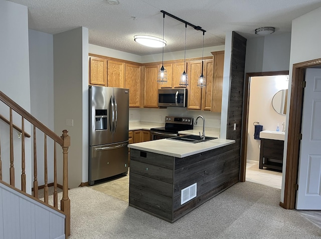 kitchen featuring sink, appliances with stainless steel finishes, a textured ceiling, decorative light fixtures, and kitchen peninsula