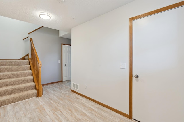 spare room featuring light hardwood / wood-style floors and a textured ceiling