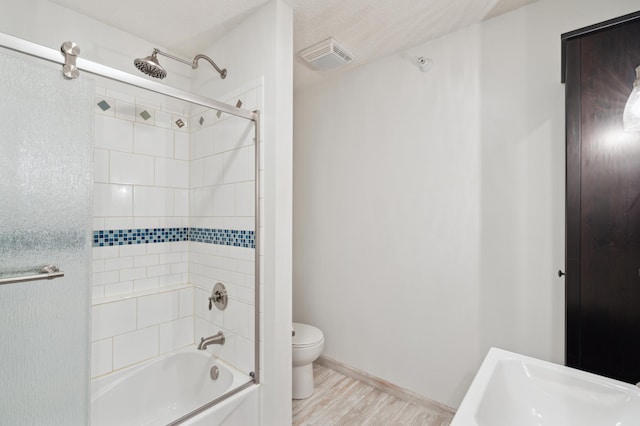 bathroom featuring wood-type flooring, toilet, and tiled shower / bath combo