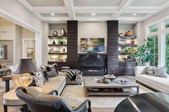 living room featuring coffered ceiling, a fireplace, beamed ceiling, and light hardwood / wood-style flooring