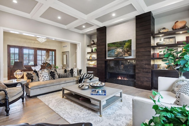 living room with beamed ceiling, a large fireplace, light hardwood / wood-style flooring, and coffered ceiling