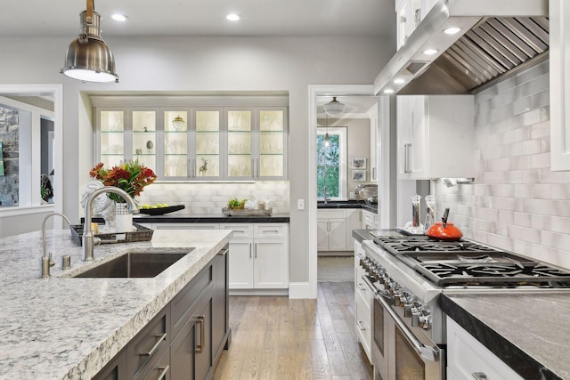 kitchen with white cabinets, sink, light hardwood / wood-style flooring, appliances with stainless steel finishes, and custom range hood