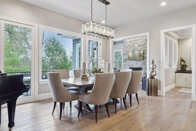 dining space with a stone fireplace, a healthy amount of sunlight, and light wood-type flooring