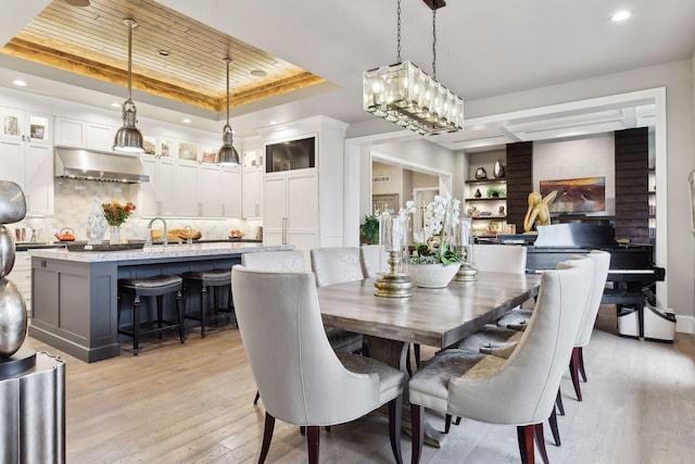 dining area featuring a raised ceiling and light hardwood / wood-style flooring