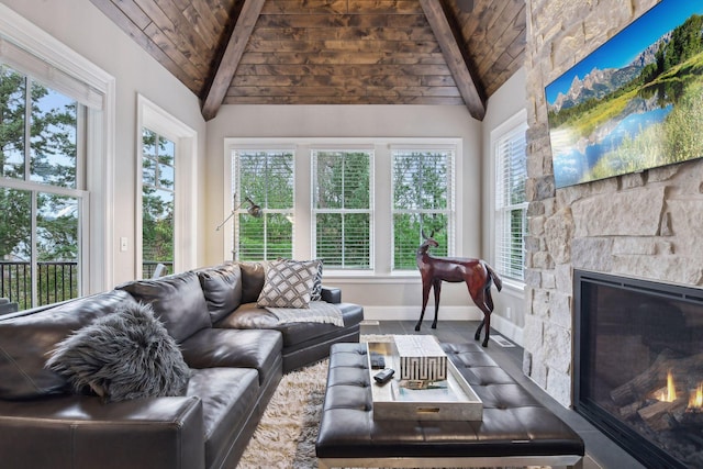 sunroom / solarium featuring a stone fireplace, lofted ceiling with beams, and wooden ceiling