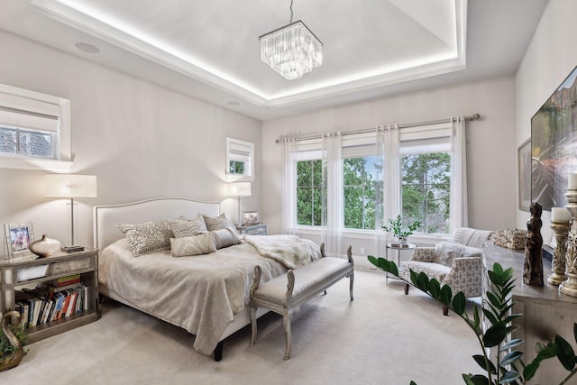 carpeted bedroom featuring a tray ceiling and a chandelier