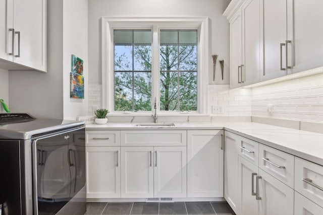 washroom featuring dark tile patterned flooring, cabinets, sink, and washer / clothes dryer