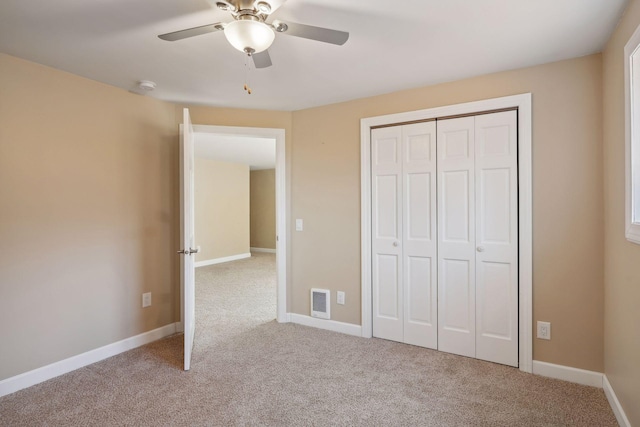 unfurnished bedroom featuring ceiling fan, a closet, and light colored carpet