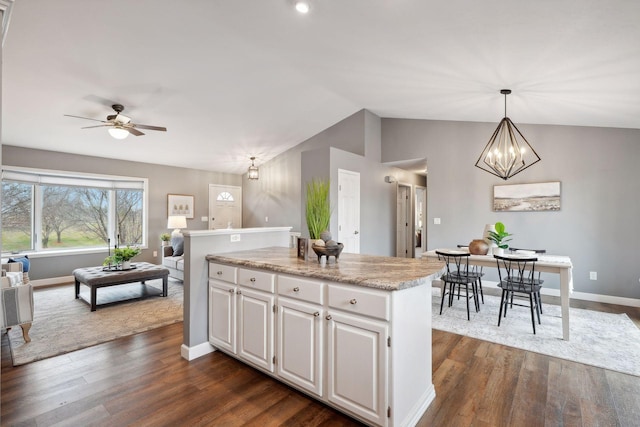 kitchen featuring white cabinets, a kitchen island, hanging light fixtures, and vaulted ceiling